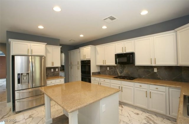 kitchen featuring white cabinets, black appliances, tasteful backsplash, and a center island