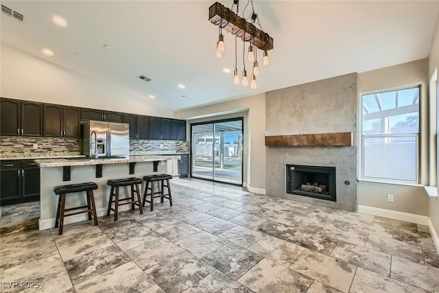 kitchen with tasteful backsplash, a kitchen island with sink, a breakfast bar area, and light stone countertops