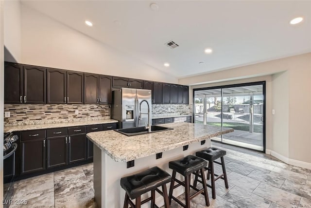 kitchen featuring lofted ceiling, backsplash, light stone counters, and sink