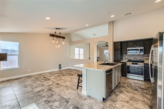 kitchen featuring stainless steel appliances, an island with sink, ceiling fan, sink, and lofted ceiling