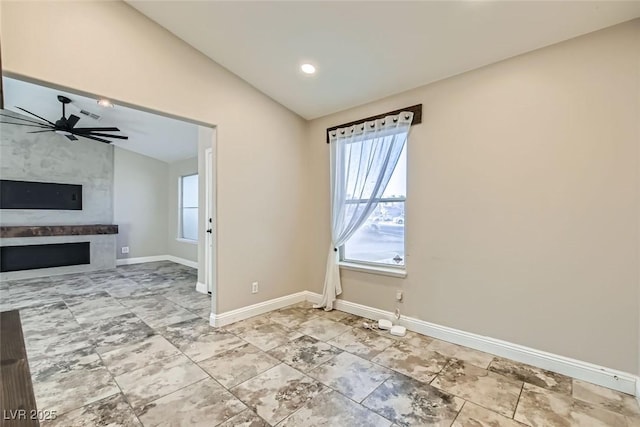 unfurnished room with ceiling fan, vaulted ceiling, and a fireplace