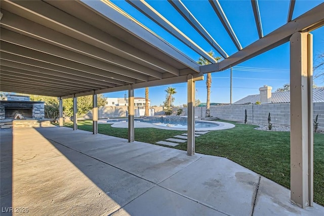 view of patio with an outdoor stone fireplace and a fenced in pool