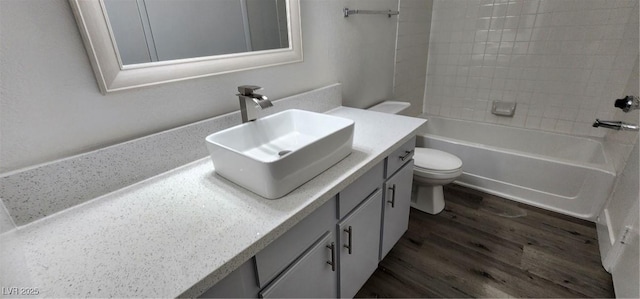 full bathroom featuring toilet, tiled shower / bath, wood-type flooring, and vanity