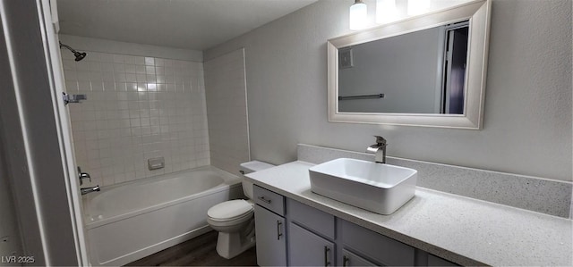 full bathroom featuring wood-type flooring, tiled shower / bath combo, vanity, and toilet