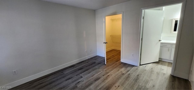 unfurnished bedroom with a walk in closet, light wood-type flooring, a closet, and ensuite bath