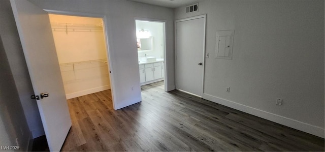 unfurnished bedroom with a walk in closet, dark wood-type flooring, a closet, and ensuite bathroom