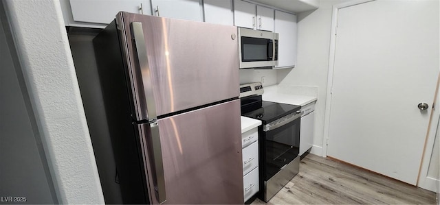 kitchen with appliances with stainless steel finishes, light hardwood / wood-style floors, and white cabinetry