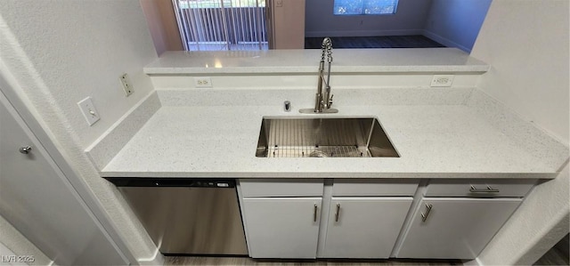 kitchen with sink, dishwasher, and light stone countertops