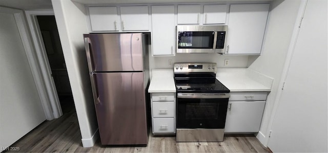 kitchen featuring light wood-type flooring, appliances with stainless steel finishes, and white cabinetry