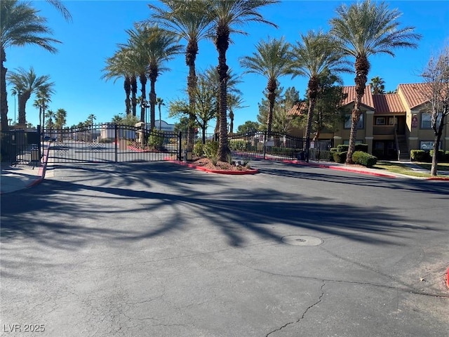 view of street featuring a gate, a gated entry, and curbs