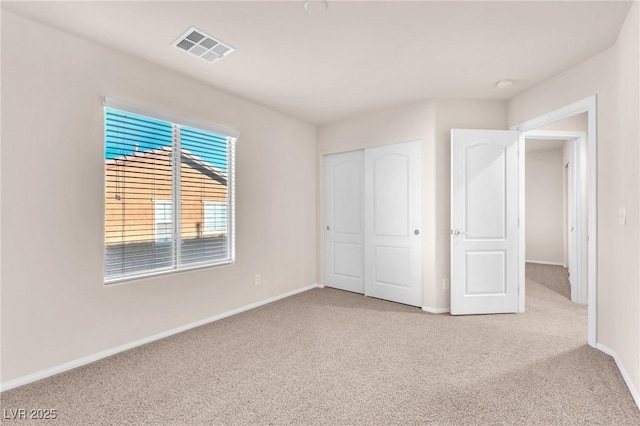 unfurnished bedroom with light colored carpet and a closet