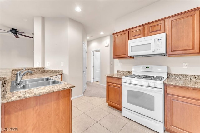 kitchen featuring light tile patterned floors, ceiling fan, white appliances, light stone counters, and sink