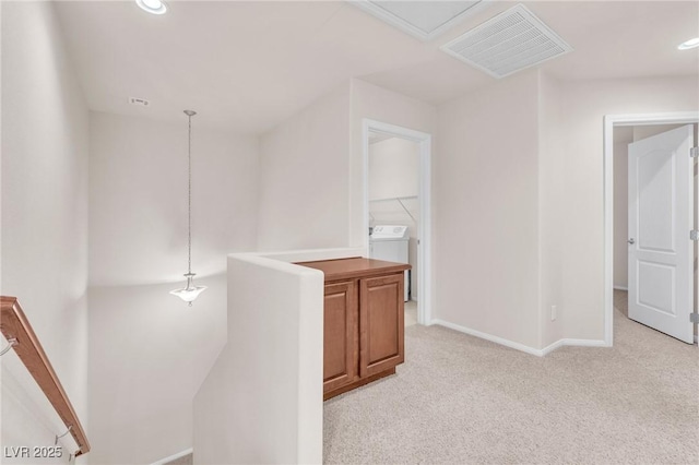 hallway featuring light colored carpet and washer / clothes dryer