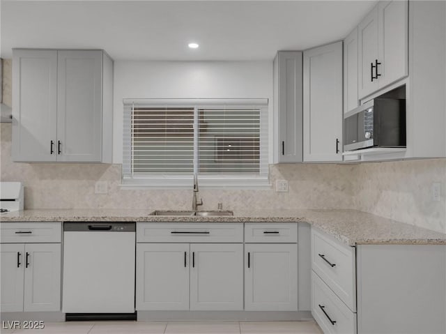 kitchen featuring white cabinets, dishwasher, light stone counters, decorative backsplash, and sink