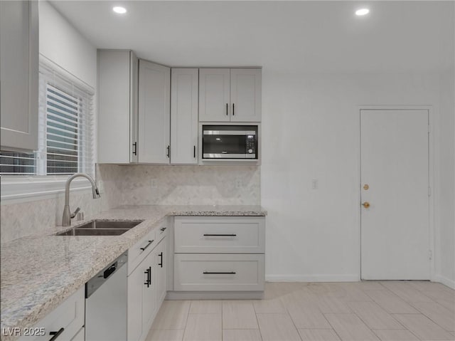 kitchen featuring light stone counters, light tile patterned floors, decorative backsplash, appliances with stainless steel finishes, and sink