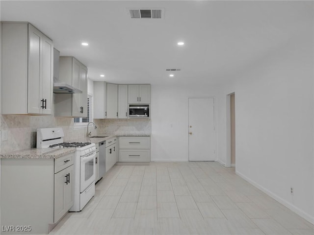 kitchen featuring appliances with stainless steel finishes, sink, wall chimney exhaust hood, white cabinets, and tasteful backsplash