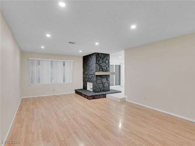 unfurnished living room featuring a fireplace and light hardwood / wood-style floors