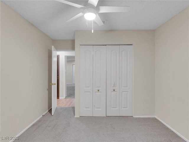 unfurnished bedroom with a closet, ceiling fan, a textured ceiling, and light colored carpet