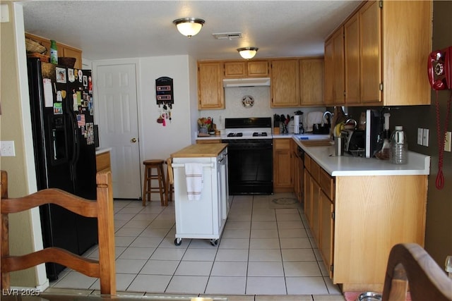 kitchen with a center island, range, black fridge, light tile patterned flooring, and sink