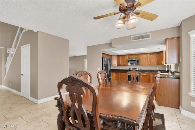 dining area featuring ceiling fan, light tile patterned floors, sink, and a textured ceiling