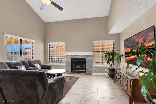 living room featuring ceiling fan, light tile patterned floors, a fireplace, and high vaulted ceiling