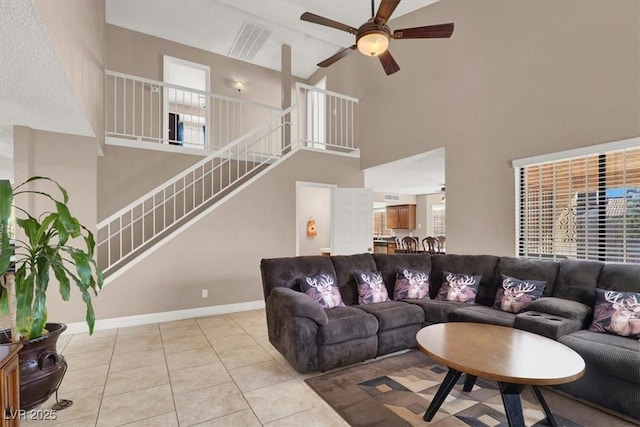 tiled living room with ceiling fan and a towering ceiling