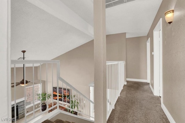 hall with carpet floors and vaulted ceiling with beams