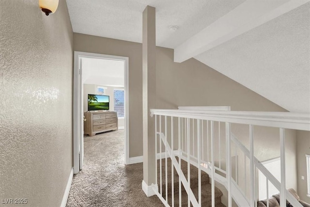 corridor featuring carpet, lofted ceiling with beams, and a textured ceiling