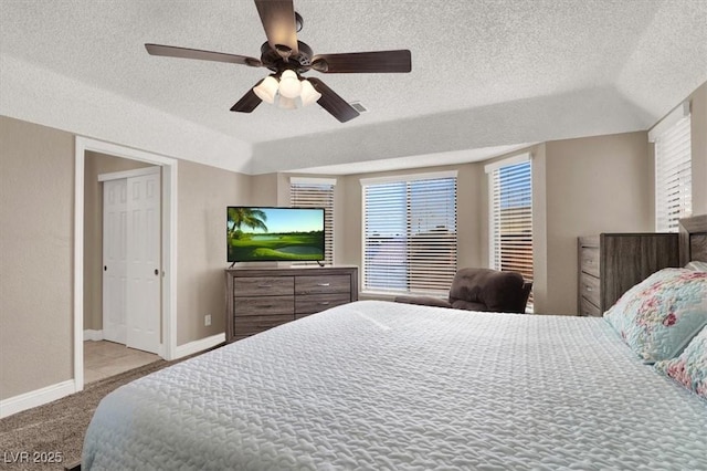 bedroom with ceiling fan, light colored carpet, and a textured ceiling