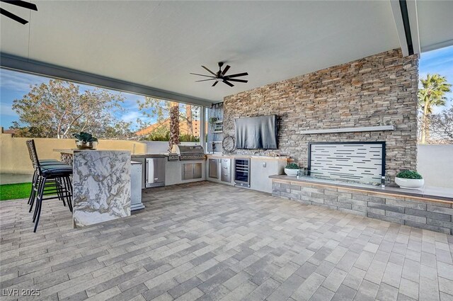 view of patio / terrace featuring an outdoor kitchen, beverage cooler, ceiling fan, and exterior bar