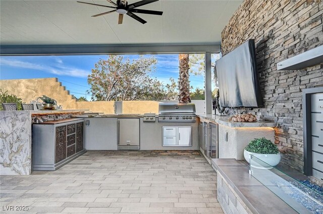 view of patio / terrace featuring exterior kitchen, ceiling fan, and a grill