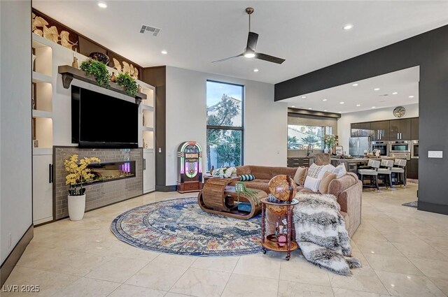 living room with built in shelves and ceiling fan