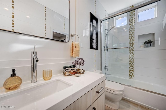 full bathroom featuring toilet, shower / bath combination with glass door, and vanity