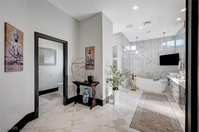 bathroom featuring tile walls, a tub to relax in, vanity, and toilet