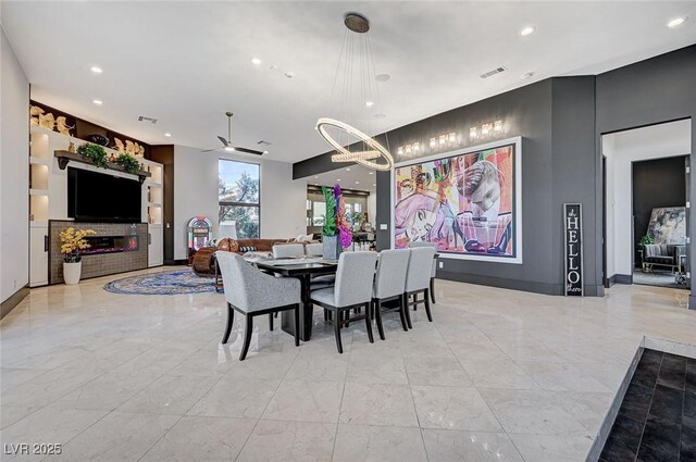 dining area featuring ceiling fan with notable chandelier and built in shelves