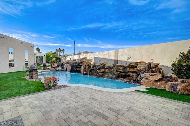 view of swimming pool with a lawn, pool water feature, and a patio area