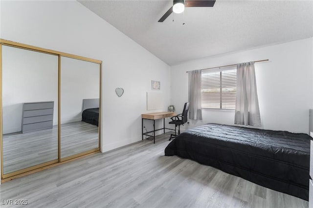 bedroom featuring vaulted ceiling, a closet, light wood-type flooring, ceiling fan, and a textured ceiling