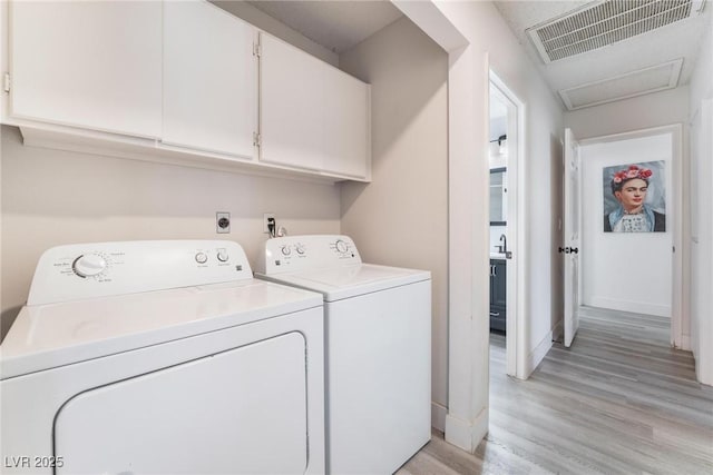 clothes washing area featuring sink, washing machine and dryer, and light hardwood / wood-style flooring