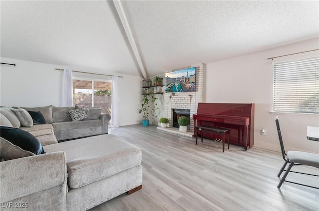 living room featuring a textured ceiling, a fireplace, vaulted ceiling with beams, and light hardwood / wood-style flooring