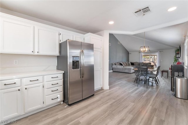 kitchen with lofted ceiling, white cabinets, stainless steel fridge, and light hardwood / wood-style floors