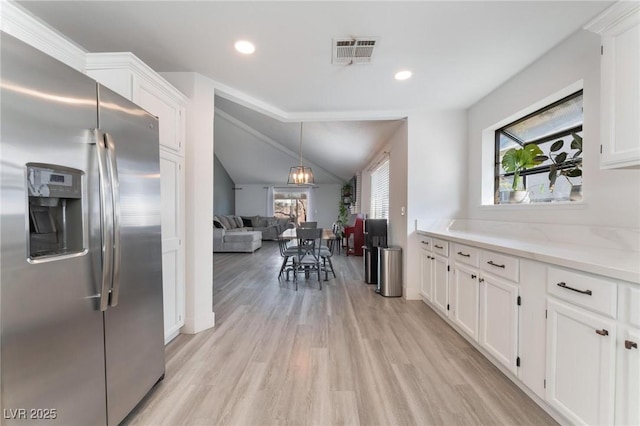 kitchen featuring vaulted ceiling, stainless steel fridge with ice dispenser, light stone counters, white cabinets, and light hardwood / wood-style flooring