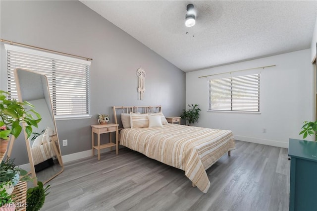 bedroom with ceiling fan, hardwood / wood-style floors, lofted ceiling, and a textured ceiling