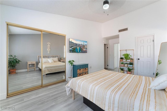 bedroom featuring light wood-type flooring, ceiling fan, and a closet