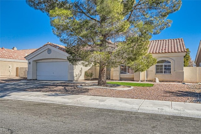 mediterranean / spanish house featuring stucco siding, fence, concrete driveway, a garage, and a tiled roof