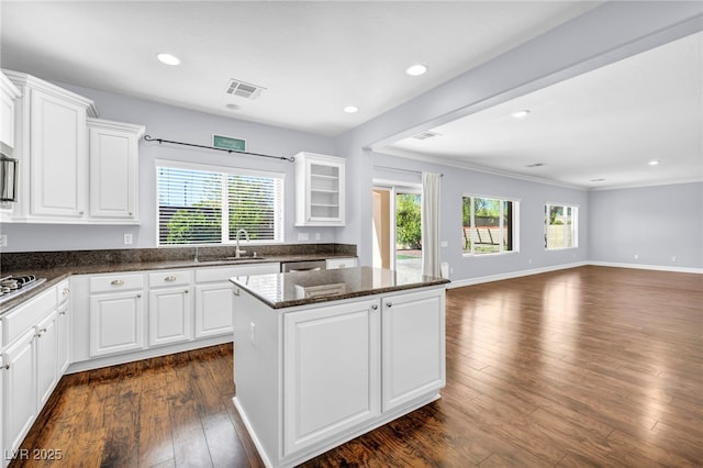 kitchen with sink, white cabinetry, dark stone counters, and a kitchen island