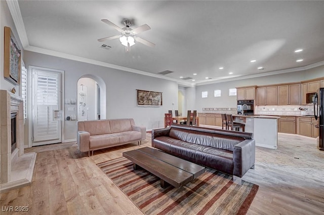 living room featuring ornamental molding, ceiling fan, and light wood-type flooring