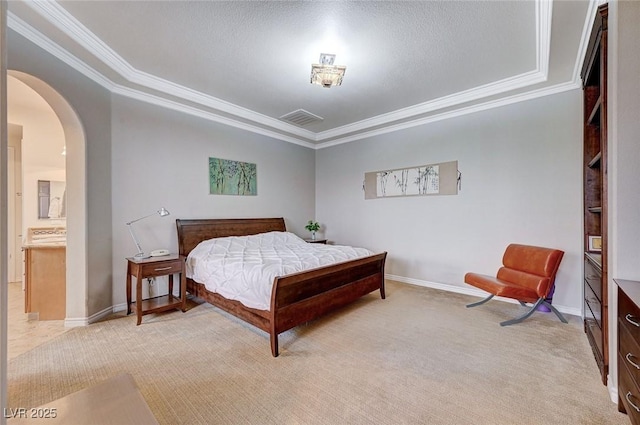 bedroom with ornamental molding, light colored carpet, and ensuite bath