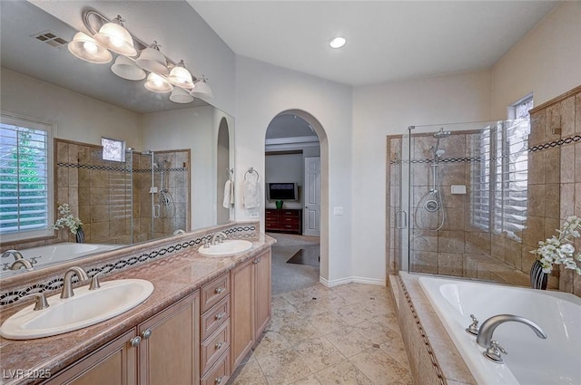 bathroom featuring independent shower and bath, a wealth of natural light, and vanity