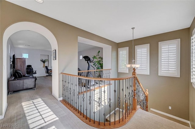 hallway with an inviting chandelier and light colored carpet