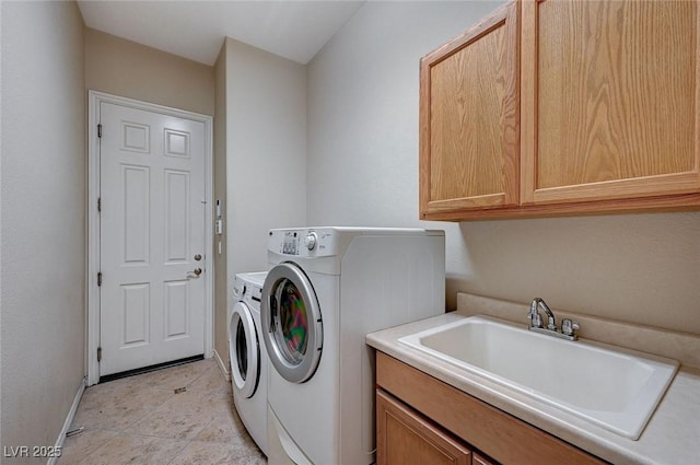 clothes washing area with washer and dryer, cabinets, light tile patterned flooring, and sink